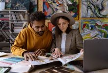 Dois profissionais analisam projetos de design em um espaço criativo.