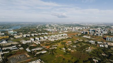 Vista aérea de Brasília, mostrando áreas urbanas, edifícios e trechos de vegetação sob a luz do dia.