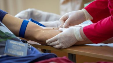 Profissional de saúde coleta sangue do braço de um doador em ambiente clínico.