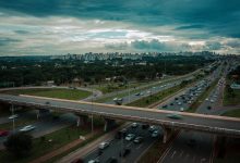 Vista aérea de Brasília com trânsito intenso em uma rodovia sob céu nublado.