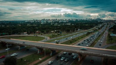 Vista aérea de Brasília com trânsito intenso em uma rodovia sob céu nublado.