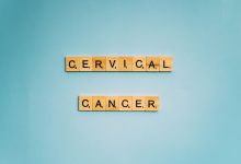 Peças de jogo de letras formam a expressão “Cervical Cancer” sobre um fundo azul-claro, em uma composição conceitual de conscientização sobre o câncer do colo do útero.